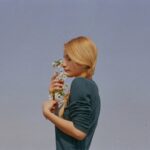 横を向いて花を持っている金髪の女性