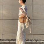 バッグを手に抱え、横向きの女性の全身写真
