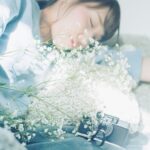 横たわっている女性とその前にある花束