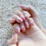 両手のアップ、ピンク色のネイルを見せているところ