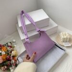 棚に置かれた小さめバッグを手に取る女性の手元