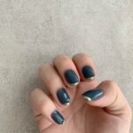 青いネイルの女性の右手アップ