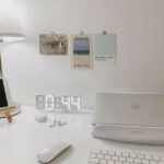机の上のパソコンやキーボード、壁に貼られた絵など