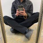 男性が足を組んで座っているところをスマートフォンで撮影している