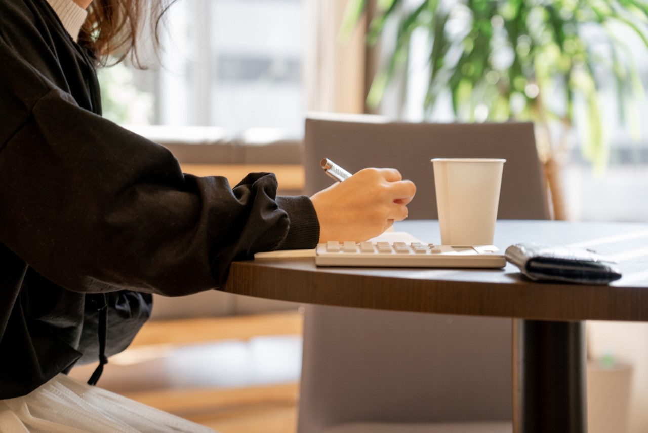 カフェで家計簿をつけている女性
