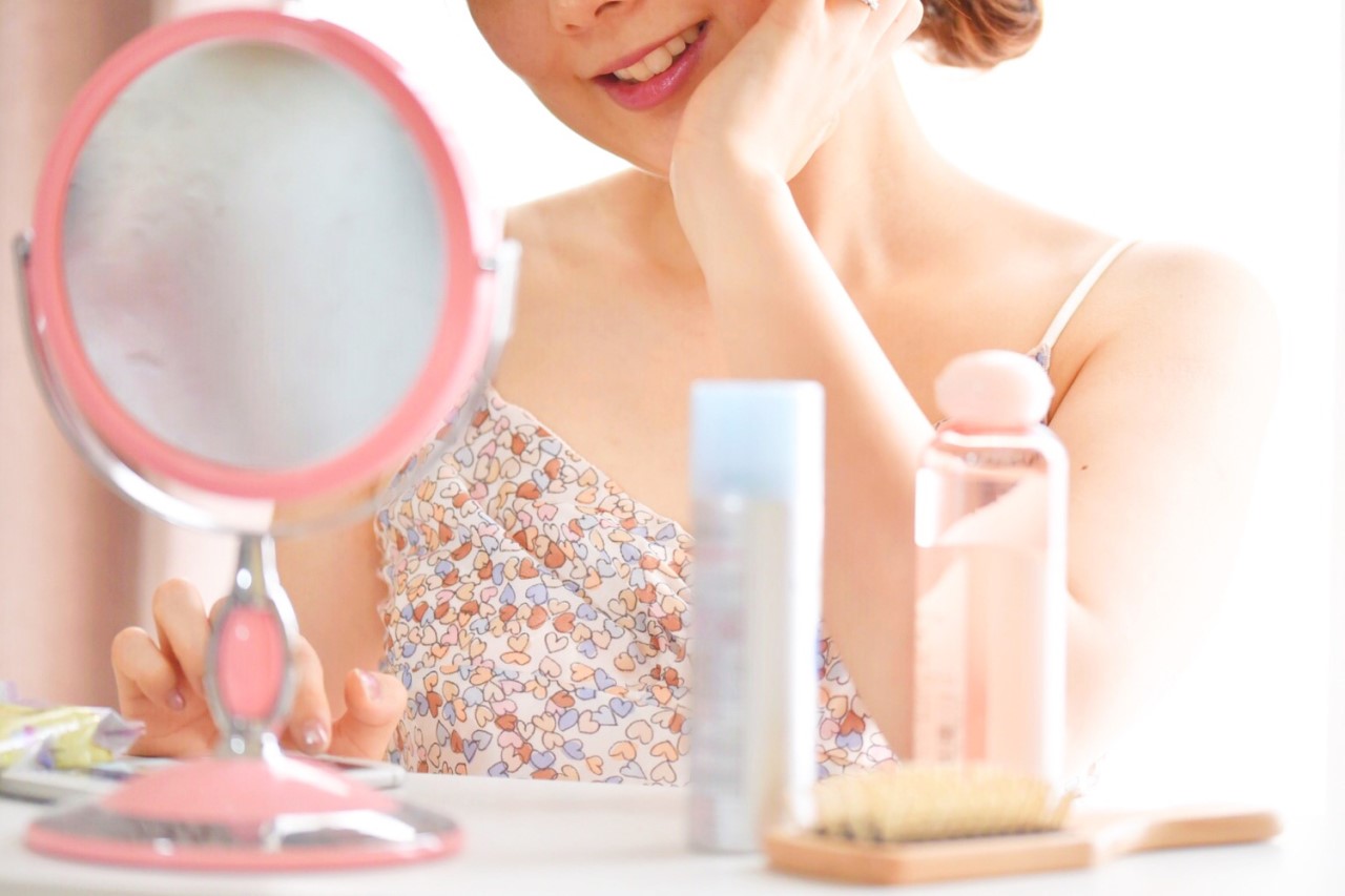 鏡を見てほほ笑む女性